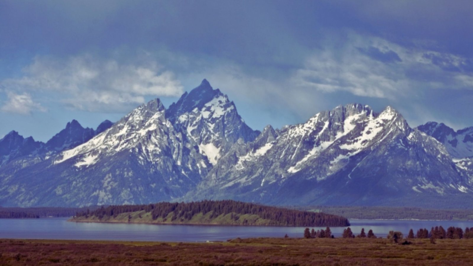 The Grand Teton Mountains rise majestically in the distance against a clear blue sky.