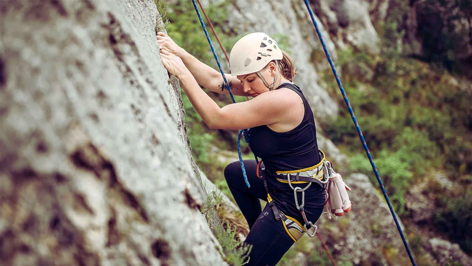  A woman climbs a rock wall, showcasing her strength and determination in an outdoor climbing environment.
