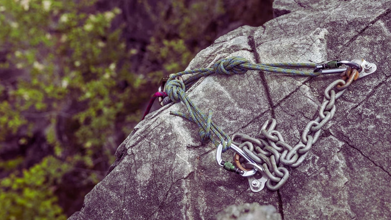 A large rock with a thick rope and a metal chain resting on its surface.