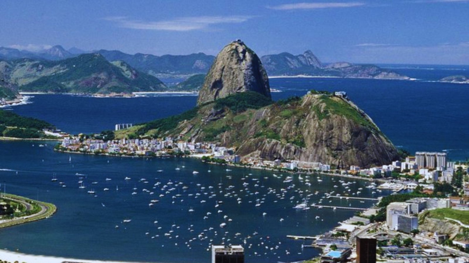 A panoramic view of Rio de Janeiro, showcasing its iconic beaches and mountains under a clear blue sky.
