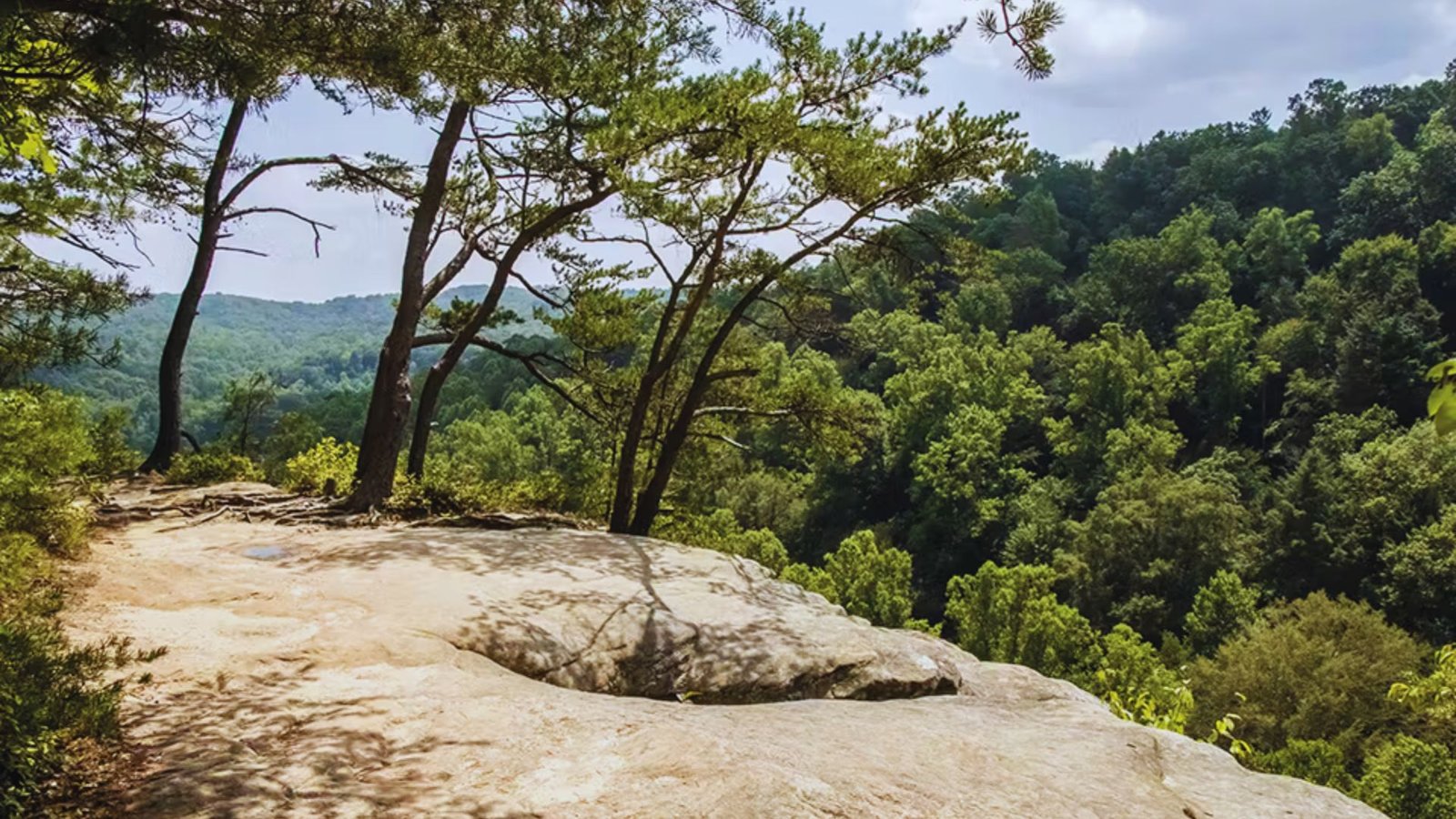  A panoramic view of majestic mountains seen from the edge of a steep cliff under a clear blue sky.
