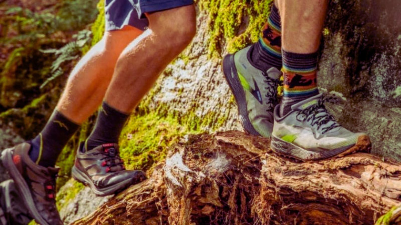 Two hikers in sturdy shoes stand on a large rock, surrounded by nature, ready for their outdoor adventure.
