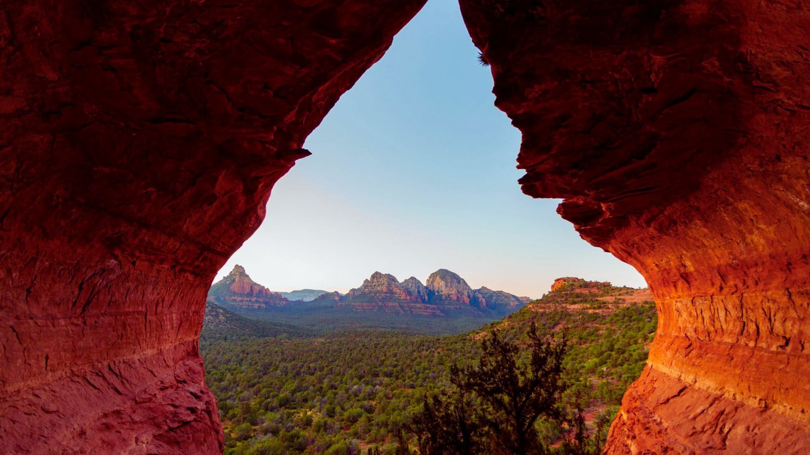 View of red rock formations framed by an arch, showcasing the natural beauty of the landscape.