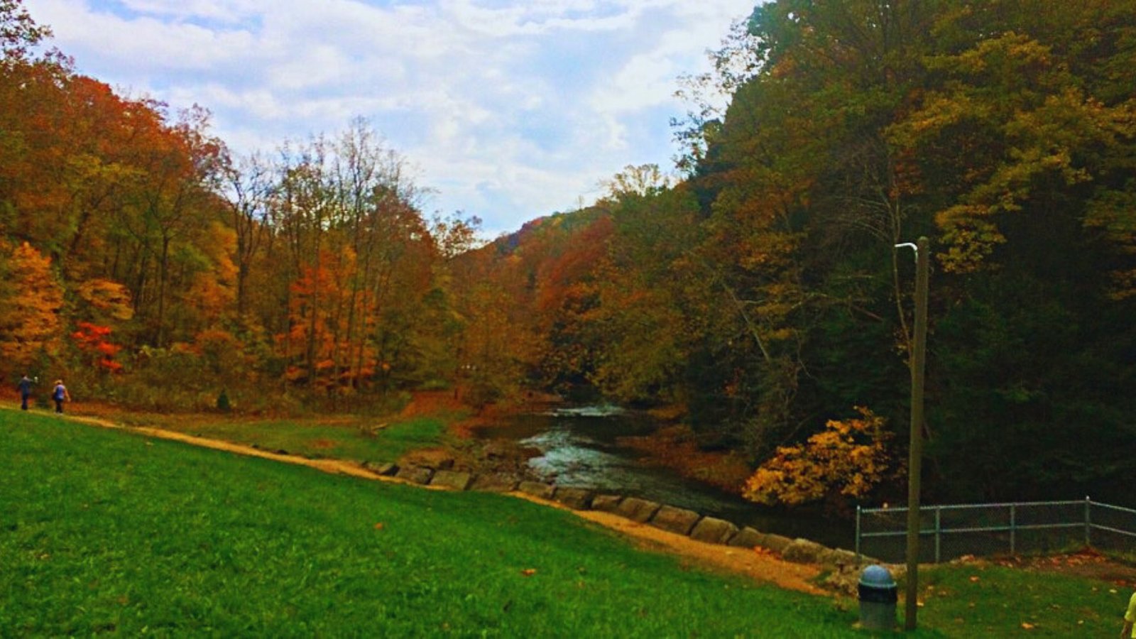A serene river view surrounded by vibrant fall foliage, showcasing shades of orange, red, and yellow.