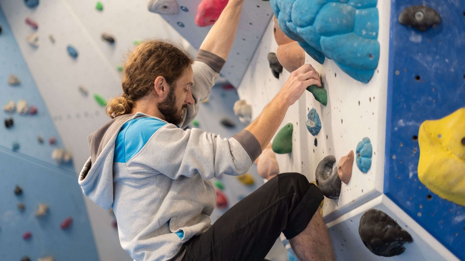 A man is climbing a rock wall, showcasing his strength and focus as he ascends the rugged surface.