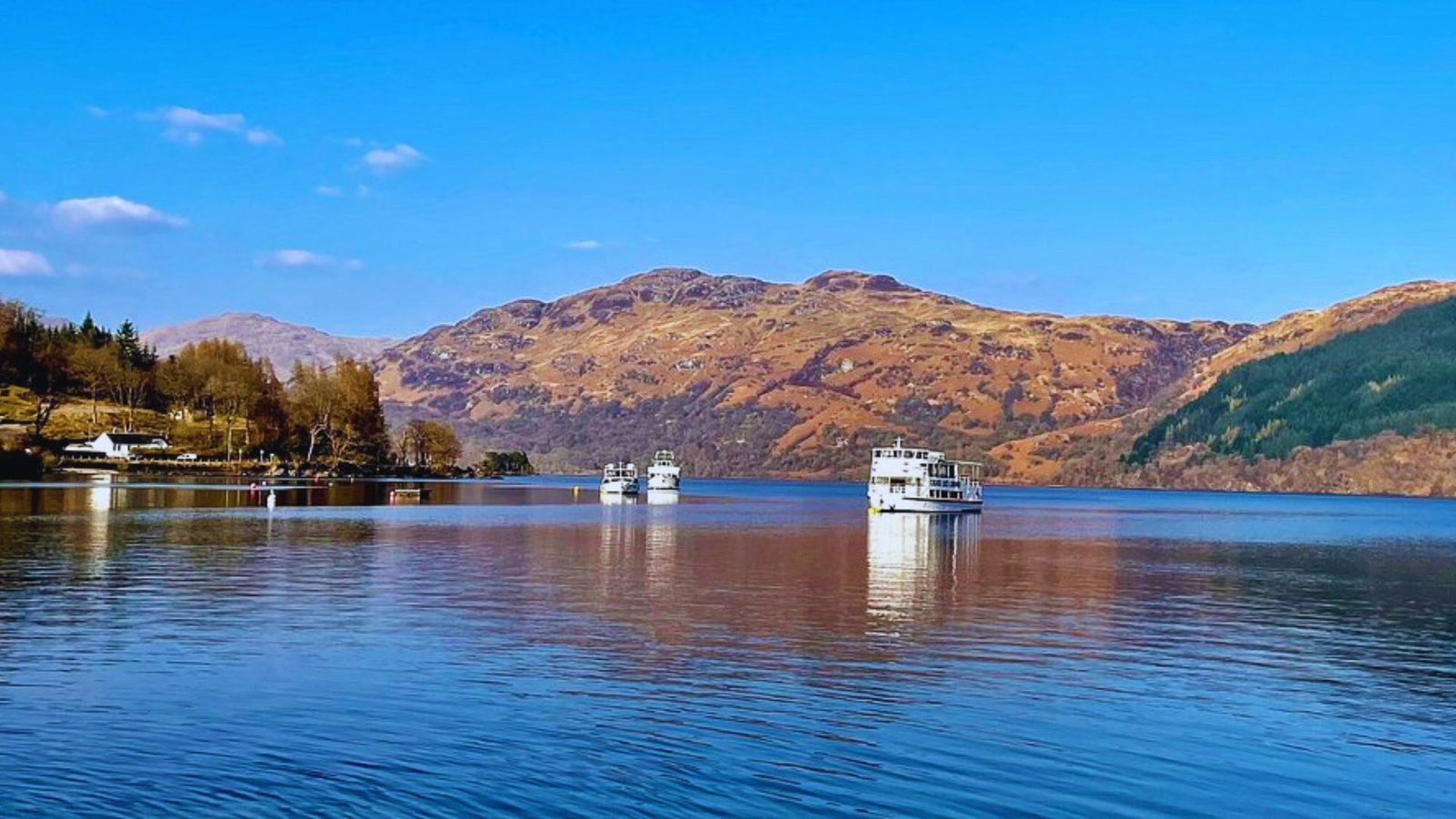 Photograph of Loch Ness, showcasing its serene waters and surrounding hills, captured by Jimmy Watson.