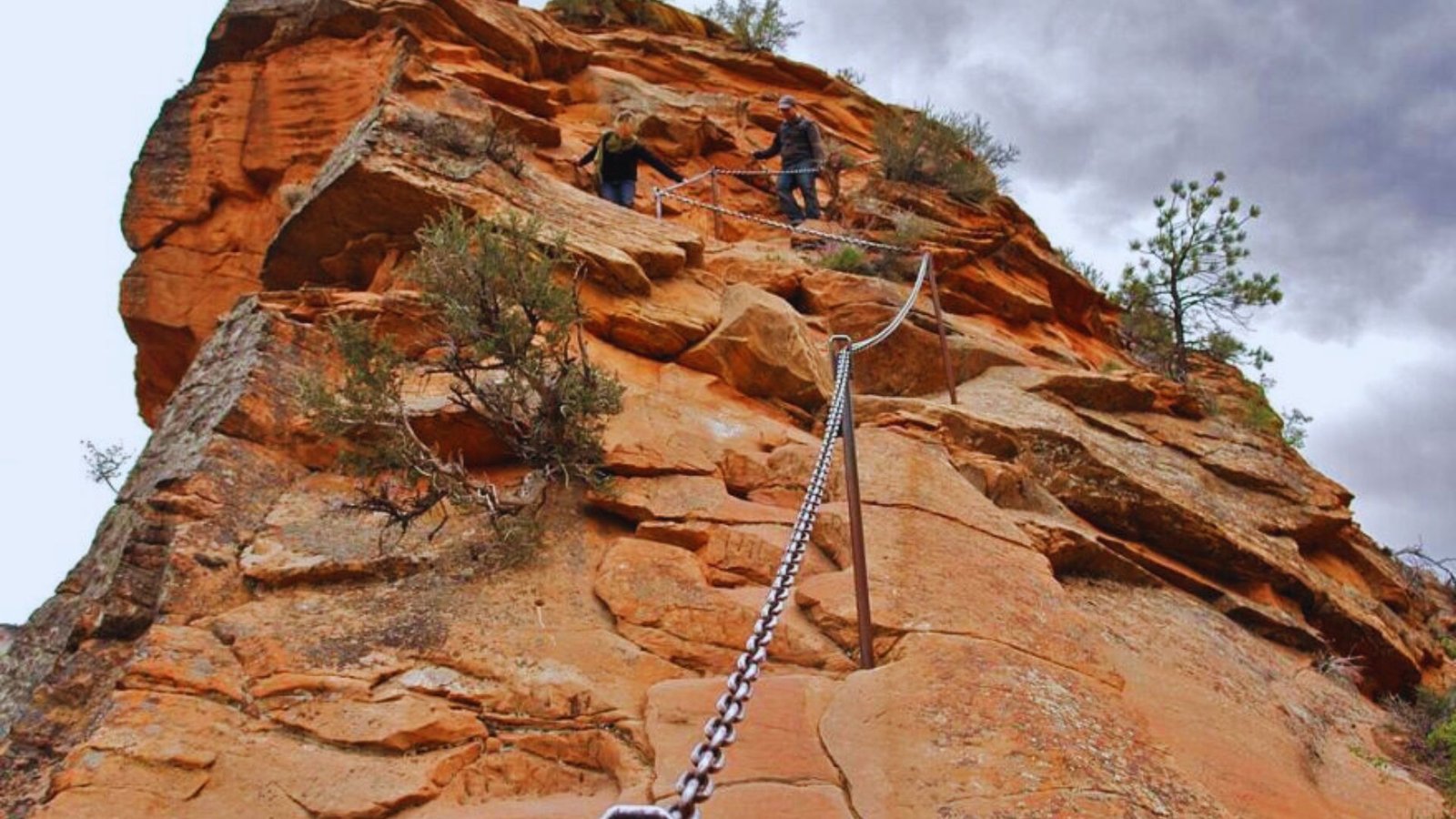 A man ascends a rocky cliff, secured by a climbing rope, showcasing his determination and skill in rock climbing.