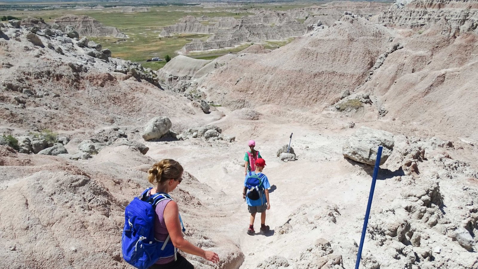 Hikers traverse the rugged terrain of the badlands, surrounded by unique rock formations and arid landscapes.