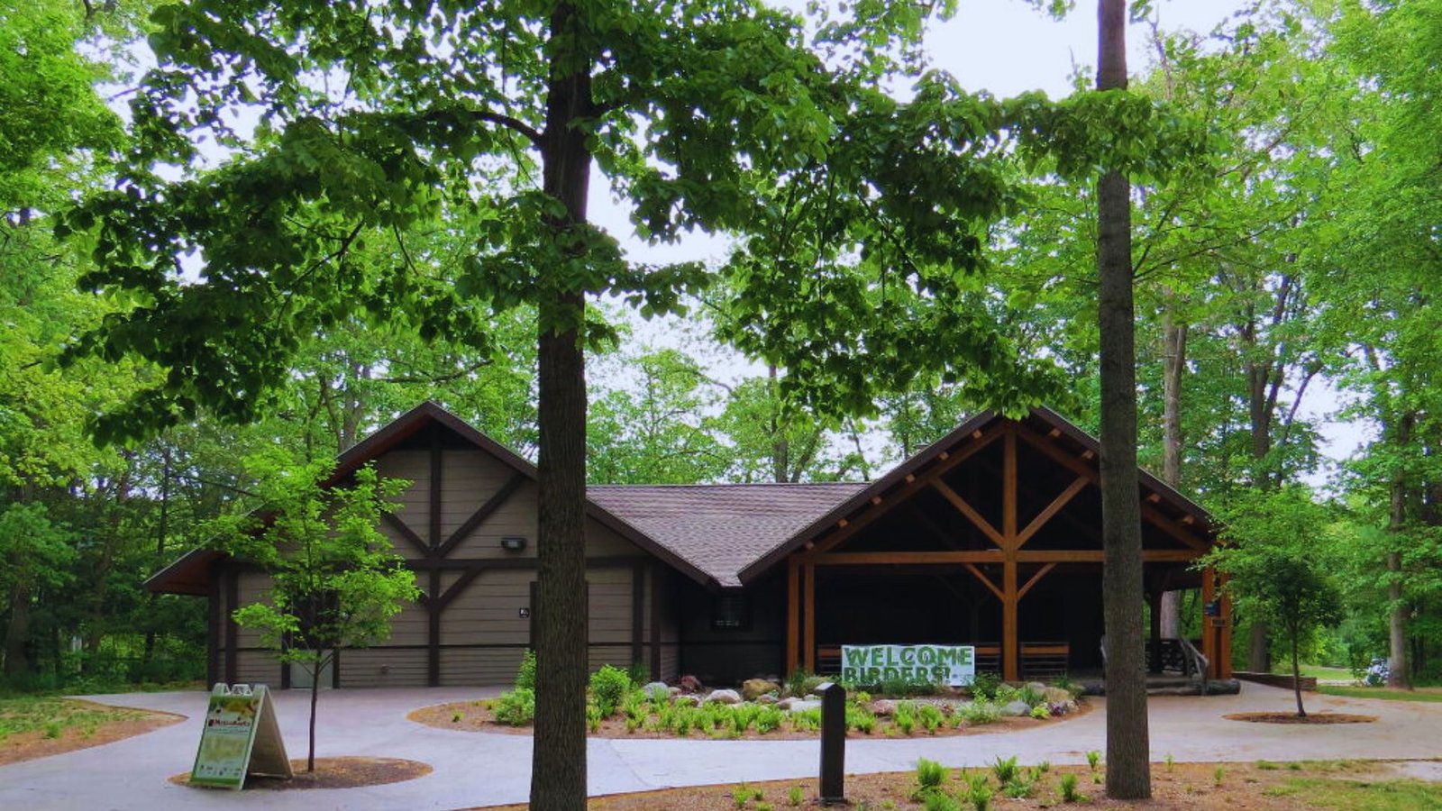  A large wooden building nestled among lush green trees in a serene natural setting.