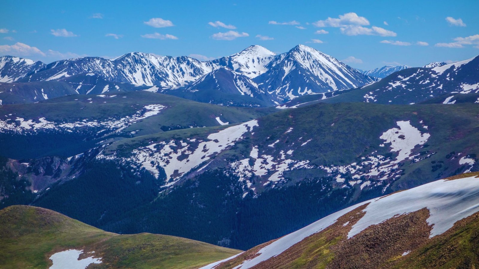 A panoramic view of majestic mountains from a high vantage point, showcasing their rugged peaks and valleys.
