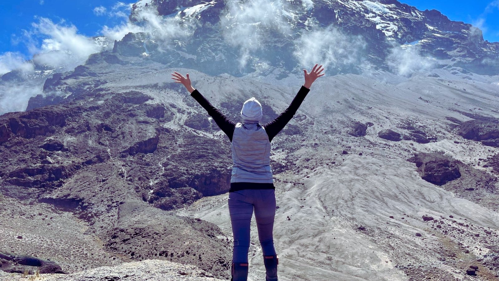  A person stands atop a mountain, arms outstretched, embracing the expansive view and the sense of freedom.