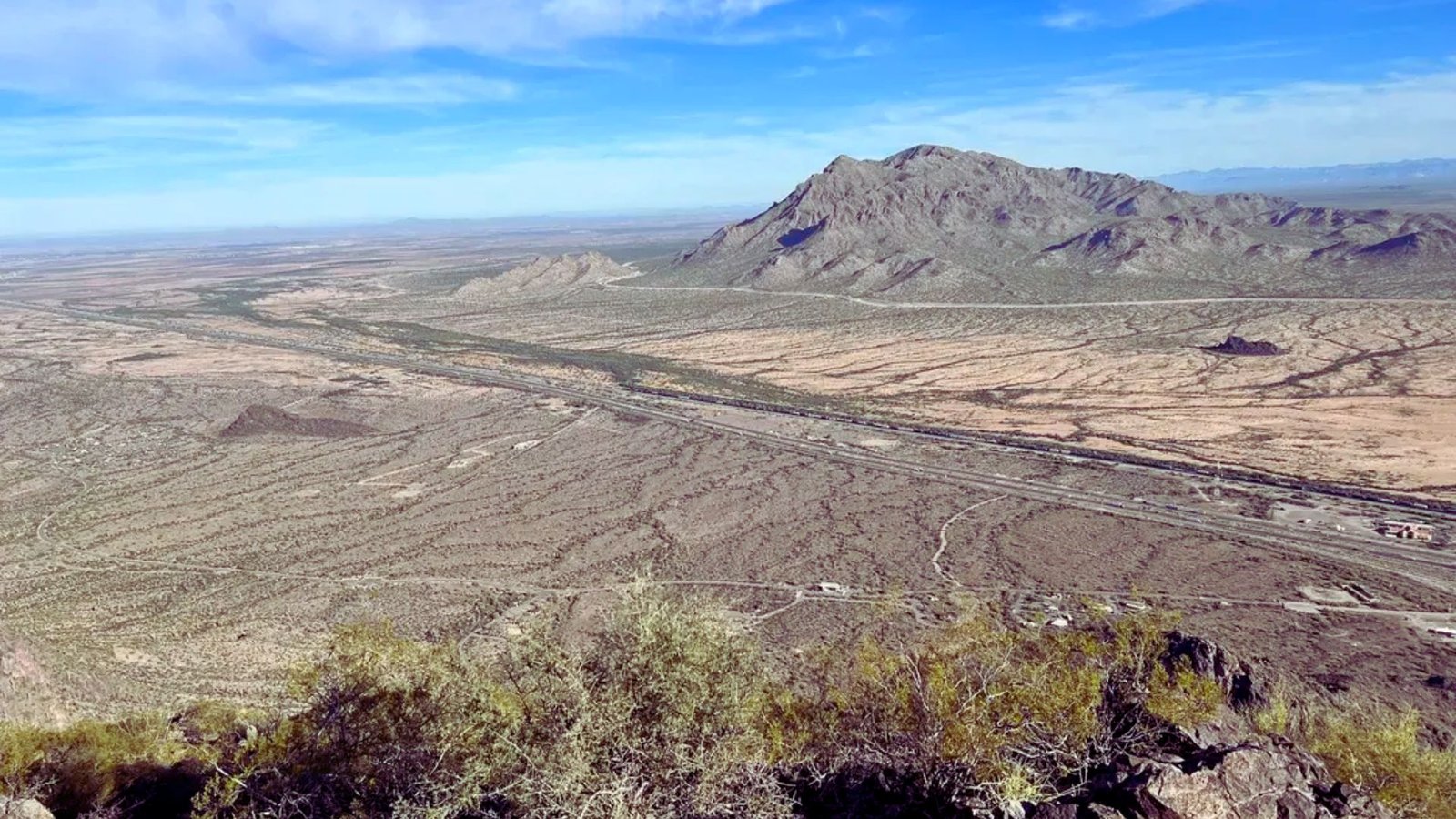  A panoramic view of a vast desert landscape from the summit of a mountain, showcasing sandy terrain and distant horizons.