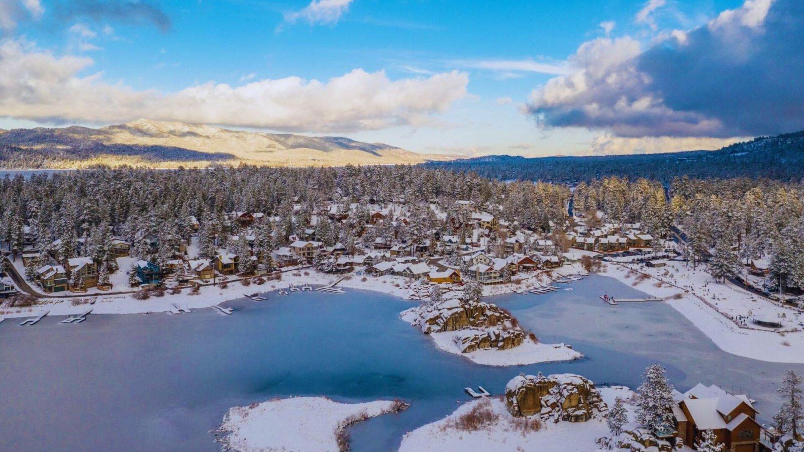 A person walks through a tunnel adorned with icicles hanging from the ceiling, creating a chilly, icy atmosphere.