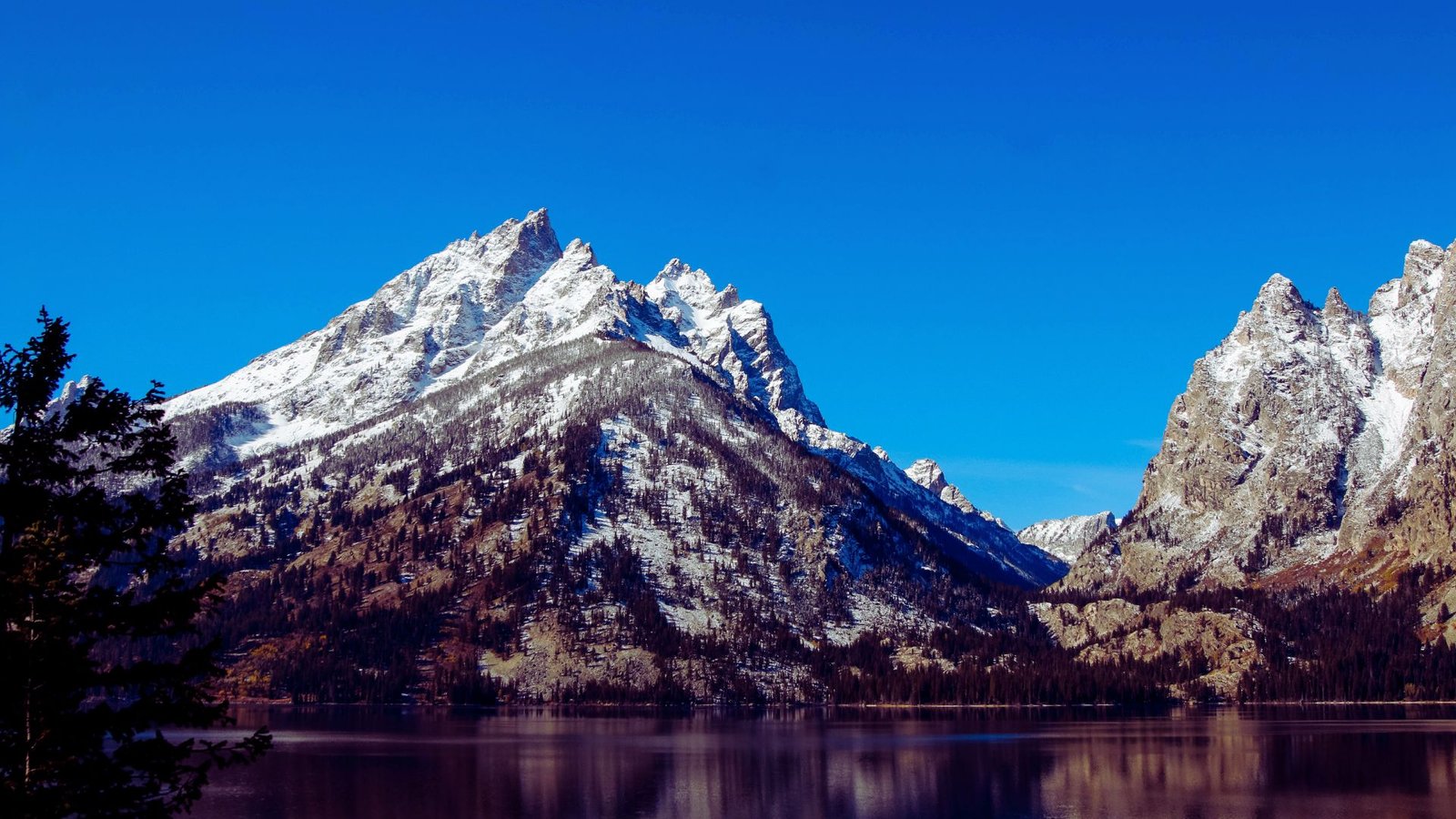 Grand Teton mountains towering above, their majestic peaks reflected in the calm water below.