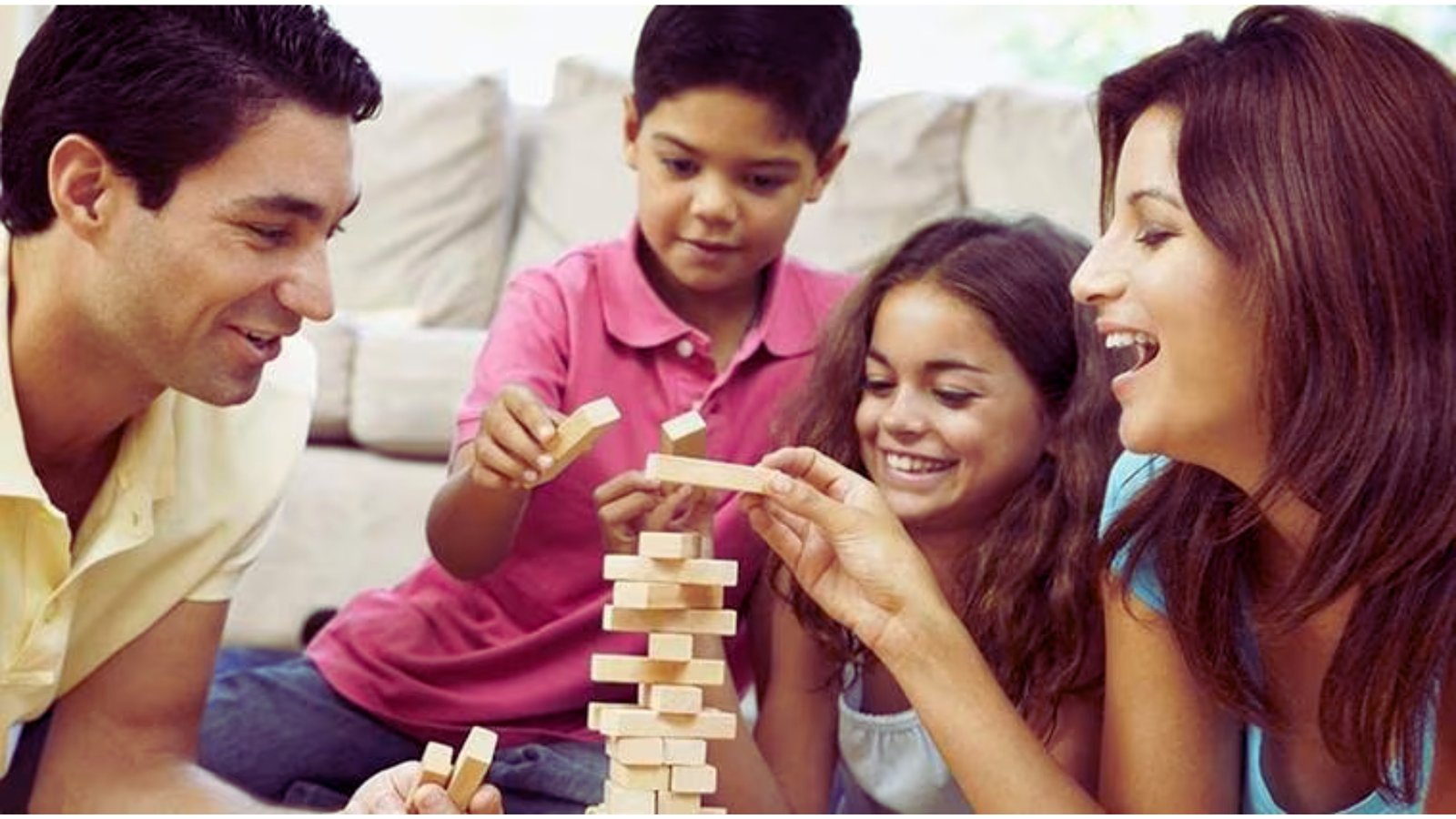 A family joyfully playing together, building structures with colorful wooden blocks on a bright, sunny day.
