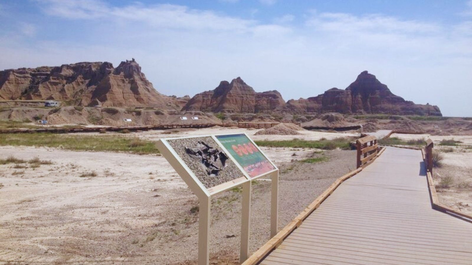 A sign stands on a boardwalk overlooking a rocky landscape, providing information about the area’s natural features.
