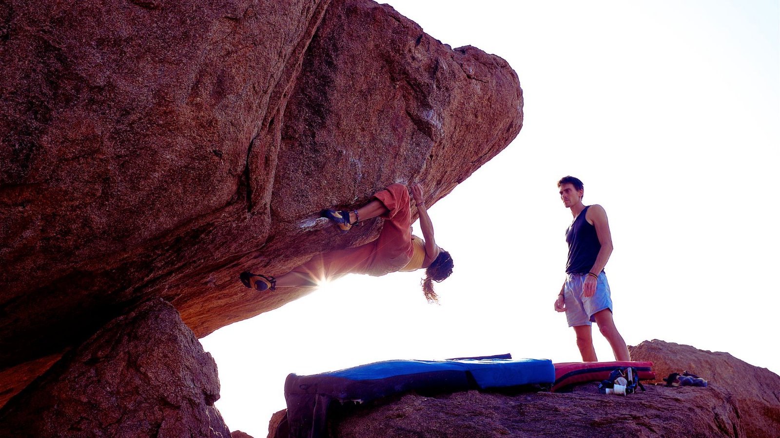 A man and a woman climbing a rocky surface, demonstrating teamwork and determination in an outdoor setting.