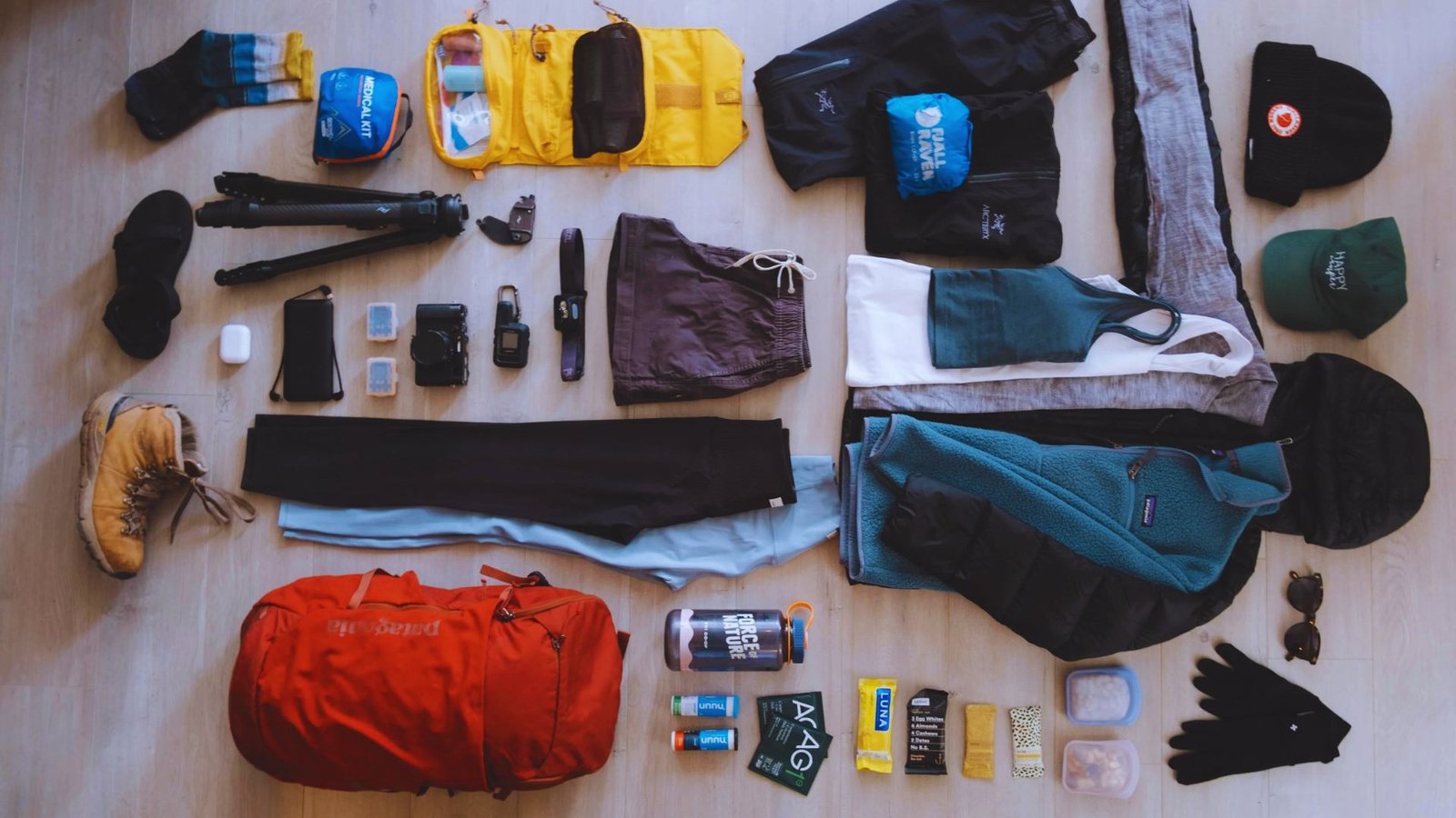 A collection of items including a backpack, hat, gloves, and various accessories arranged on a flat surface.