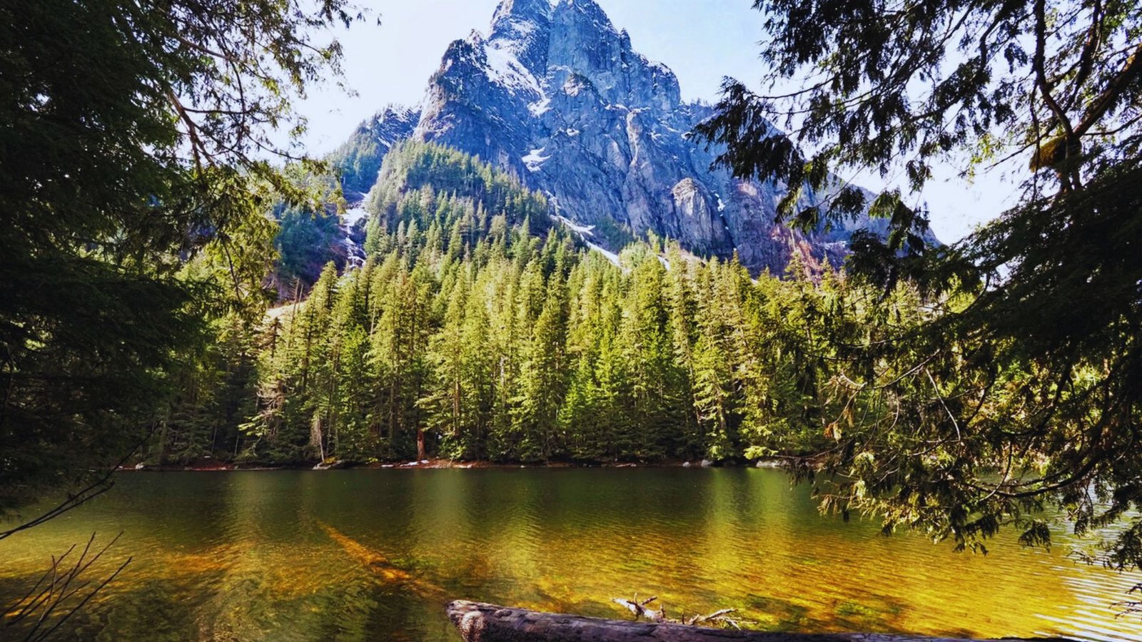 A scenic view of Barclay Lake surrounded by trees, with a majestic mountain in the background, ideal for hiking.
