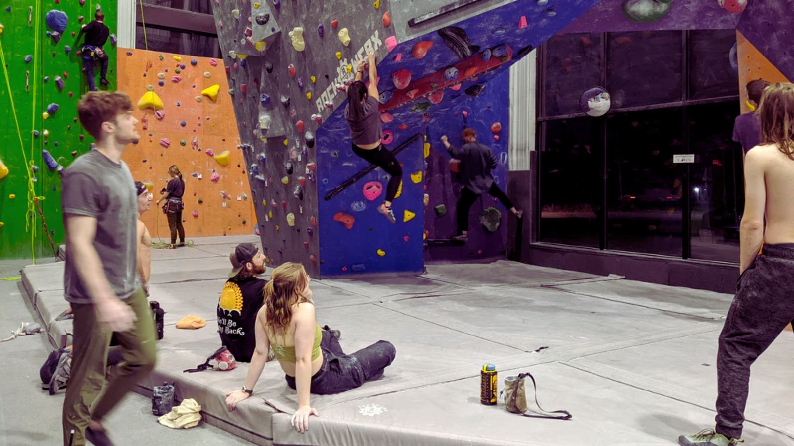 A group of people climbing a wall, showcasing teamwork and determination in an indoor climbing gym.

