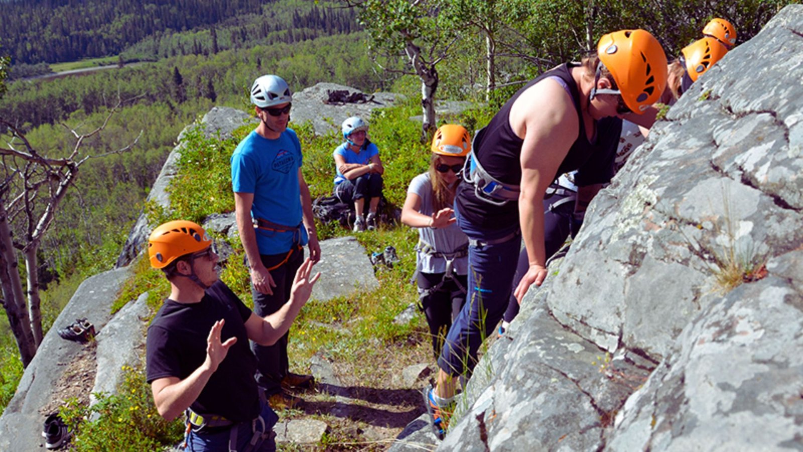 A group of individuals participating in a rock climbing course, focused on climbing techniques and safety measures.