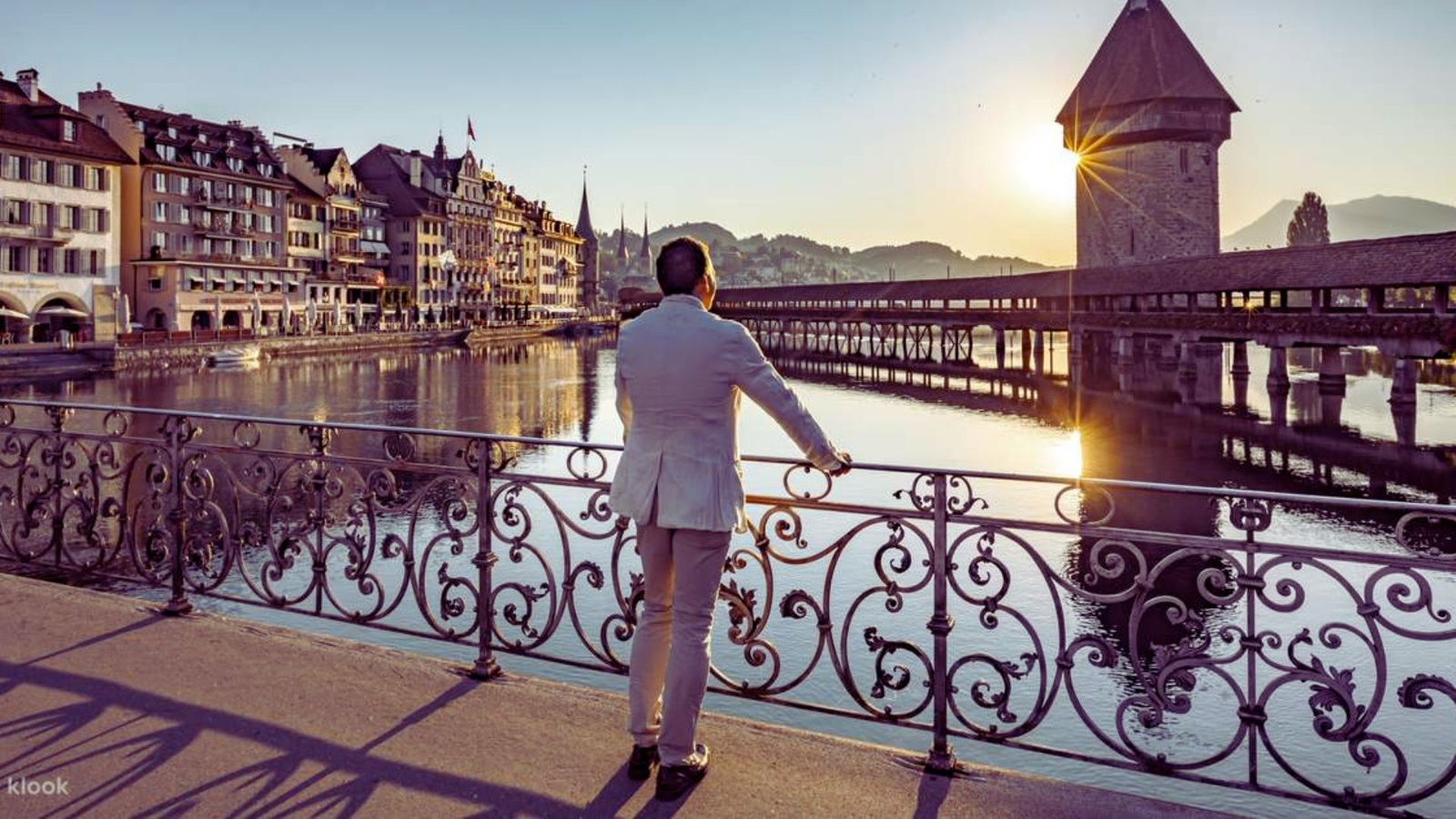  A man in a suit stands on a bridge, gazing at the river below.