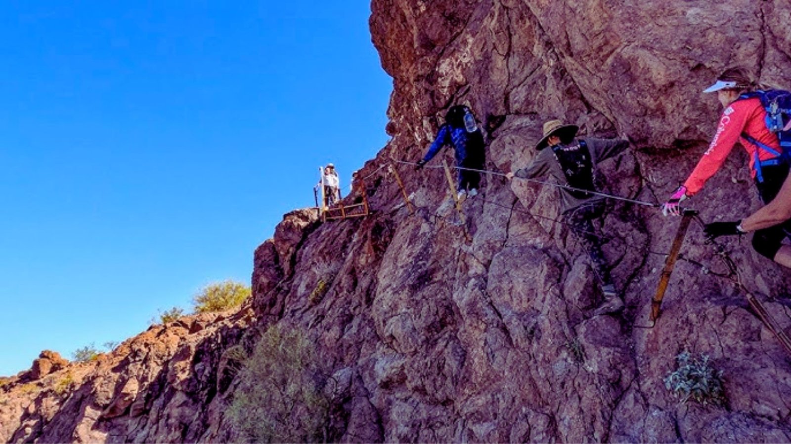 A group of people climbing a steep mountain, showcasing their determination and teamwork against a rugged landscape.