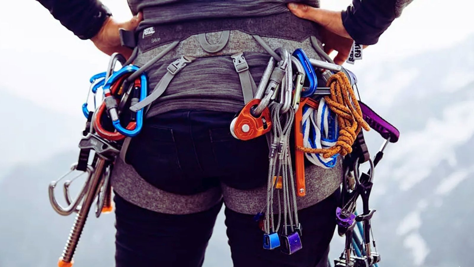 A person wearing a backpack filled with climbing gear, ready for an outdoor adventure.