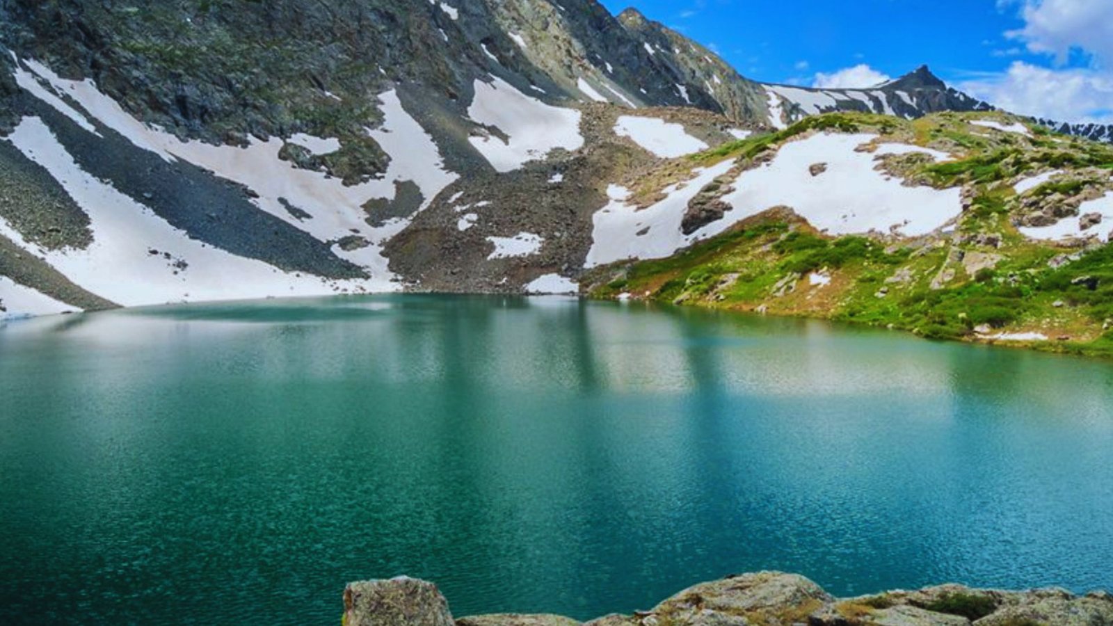 A serene lake nestled among majestic mountains, with a blanket of snow covering the peaks.