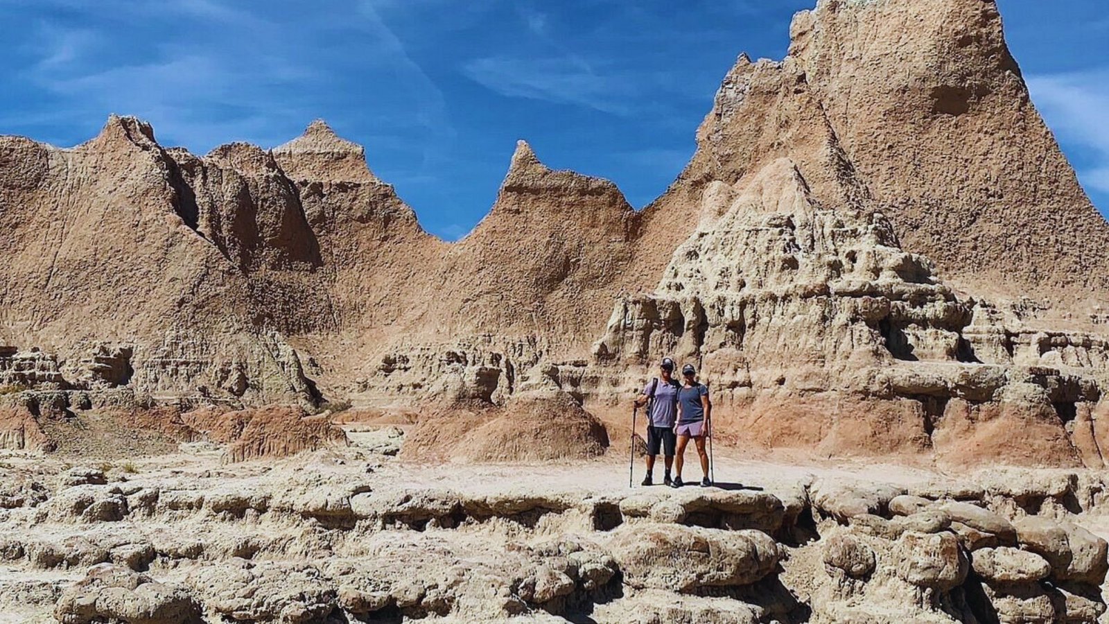  A man stands before towering rock formations, showcasing the natural landscape's rugged beauty.