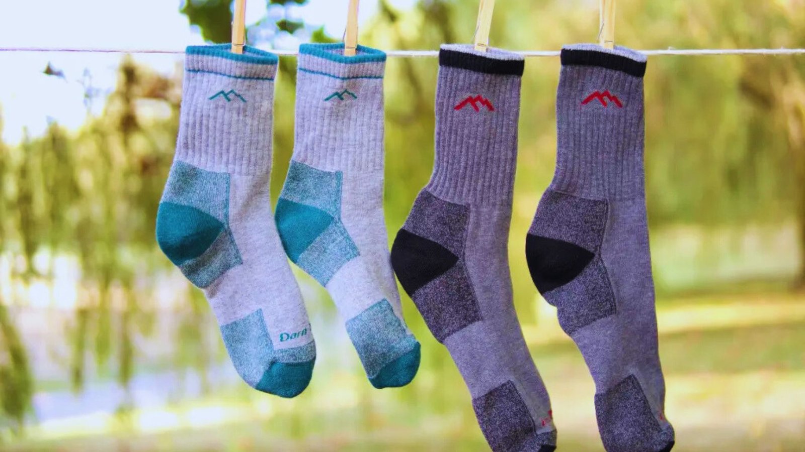 Three pairs of colorful socks hanging on a clothesline against a clear blue sky.