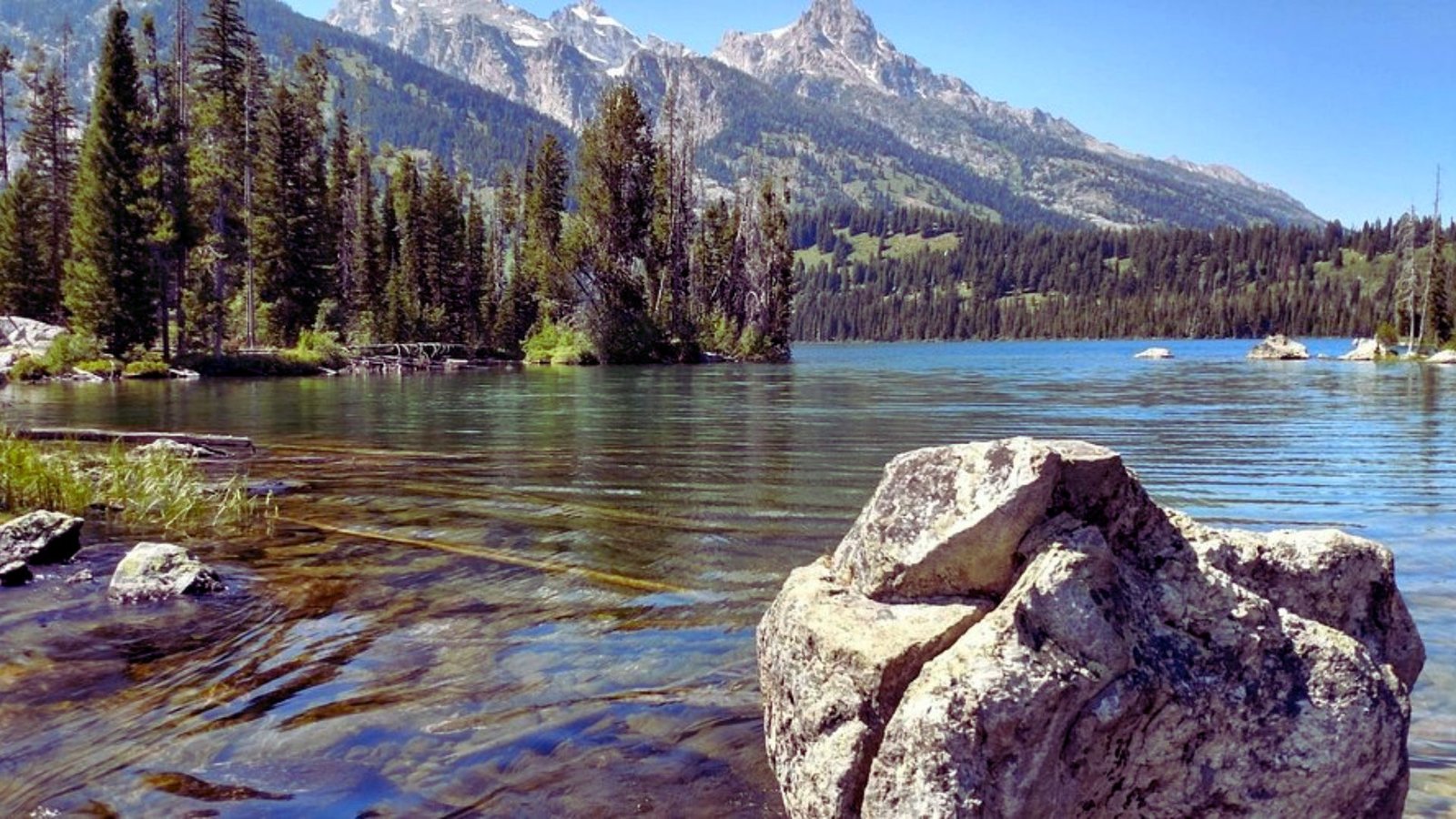 A serene lake surrounded by rocks and trees in the foreground, reflecting the natural beauty of the landscape.