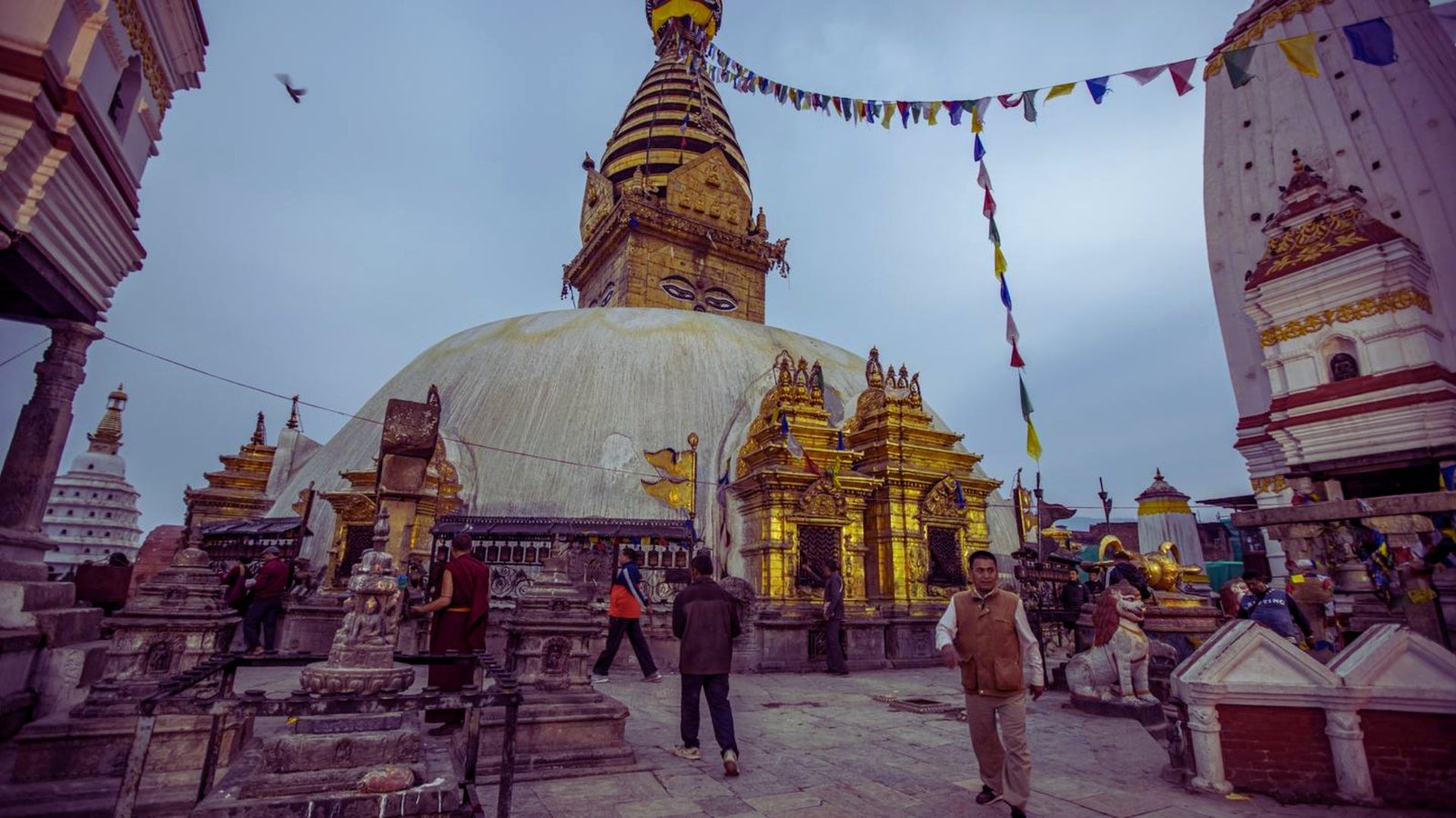  A large golden pagoda surrounded by people walking and visiting its intricate architecture and serene atmosphere.
