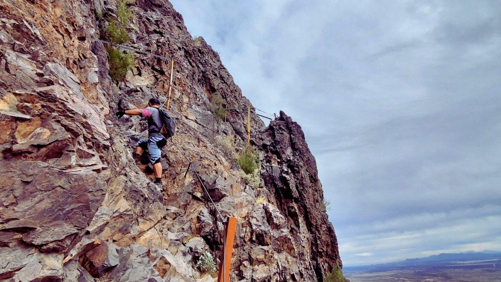 A person scaling a steep, rocky mountain, demonstrating determination and skill in a challenging outdoor environment.