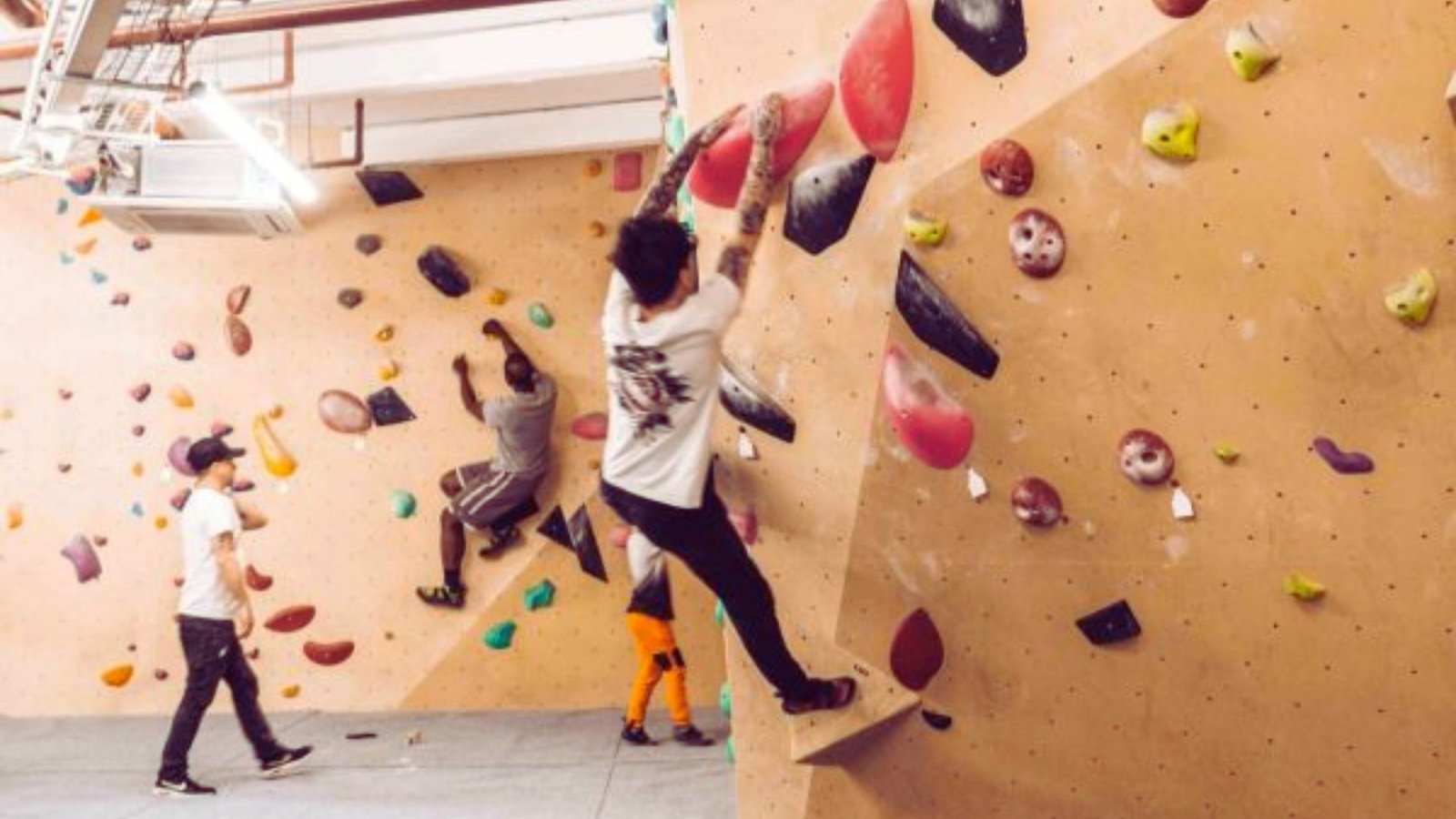  A group of diverse individuals climbing a vertical climbing wall, focused on reaching the top.