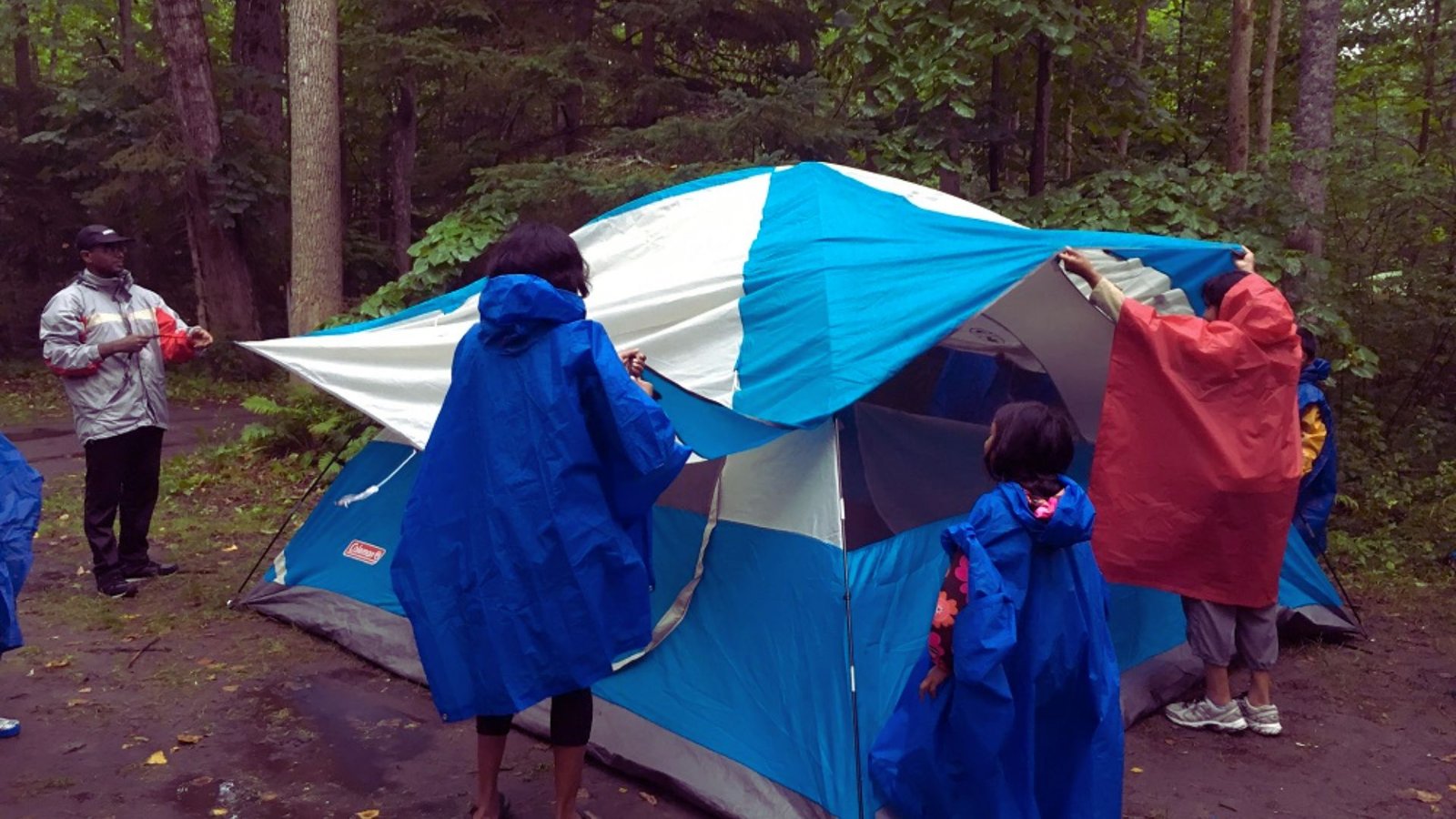  A group of people gathered around a tent, engaged in conversation and enjoying the outdoor setting.
