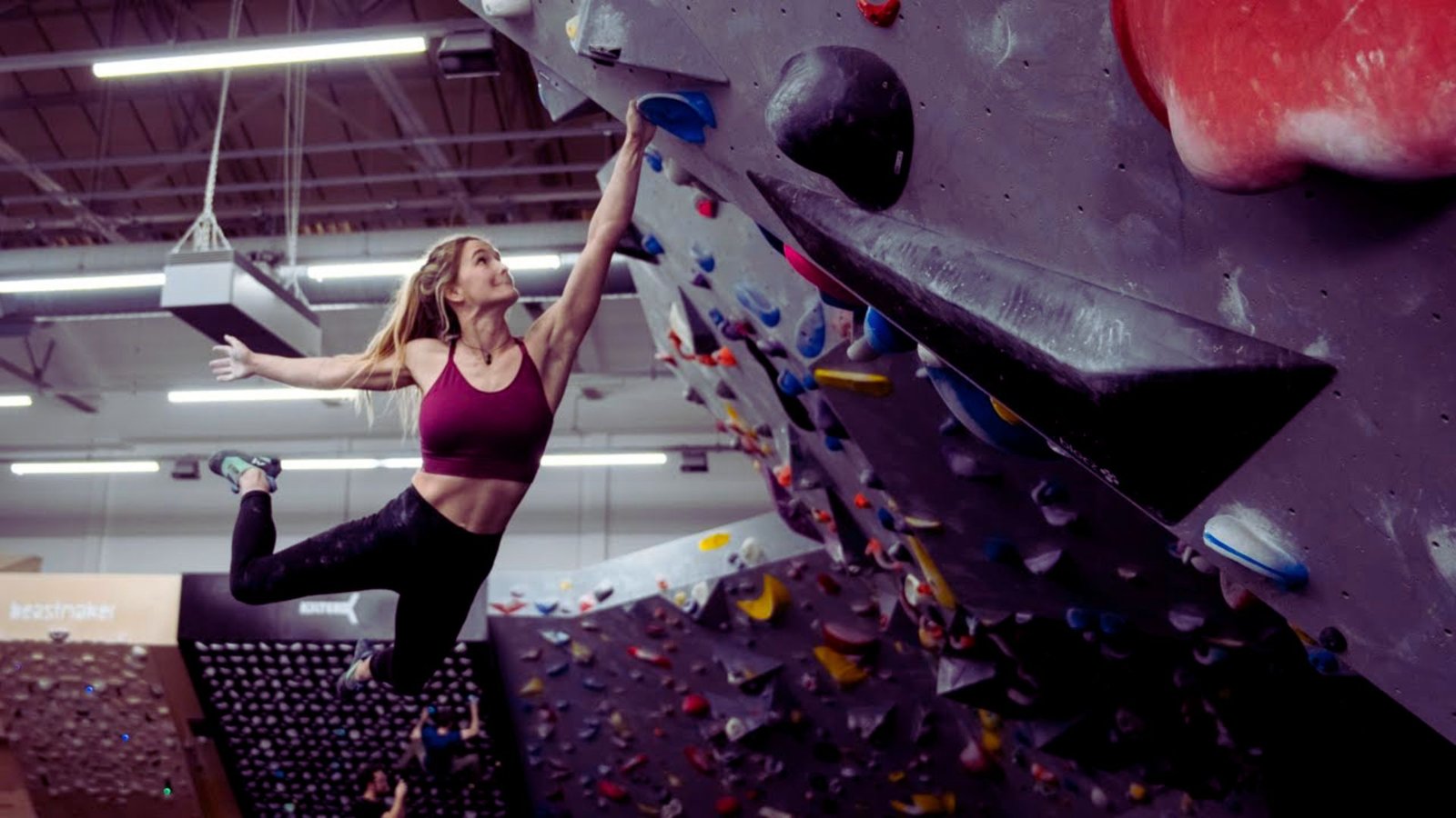 A woman climbs a rock wall, showcasing her strength and determination in an outdoor climbing environment.