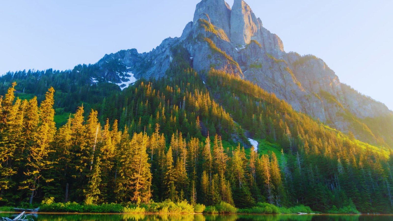 A scenic view of Barclay Lake with trees in the foreground and a mountain backdrop, perfect for hiking in Washington.