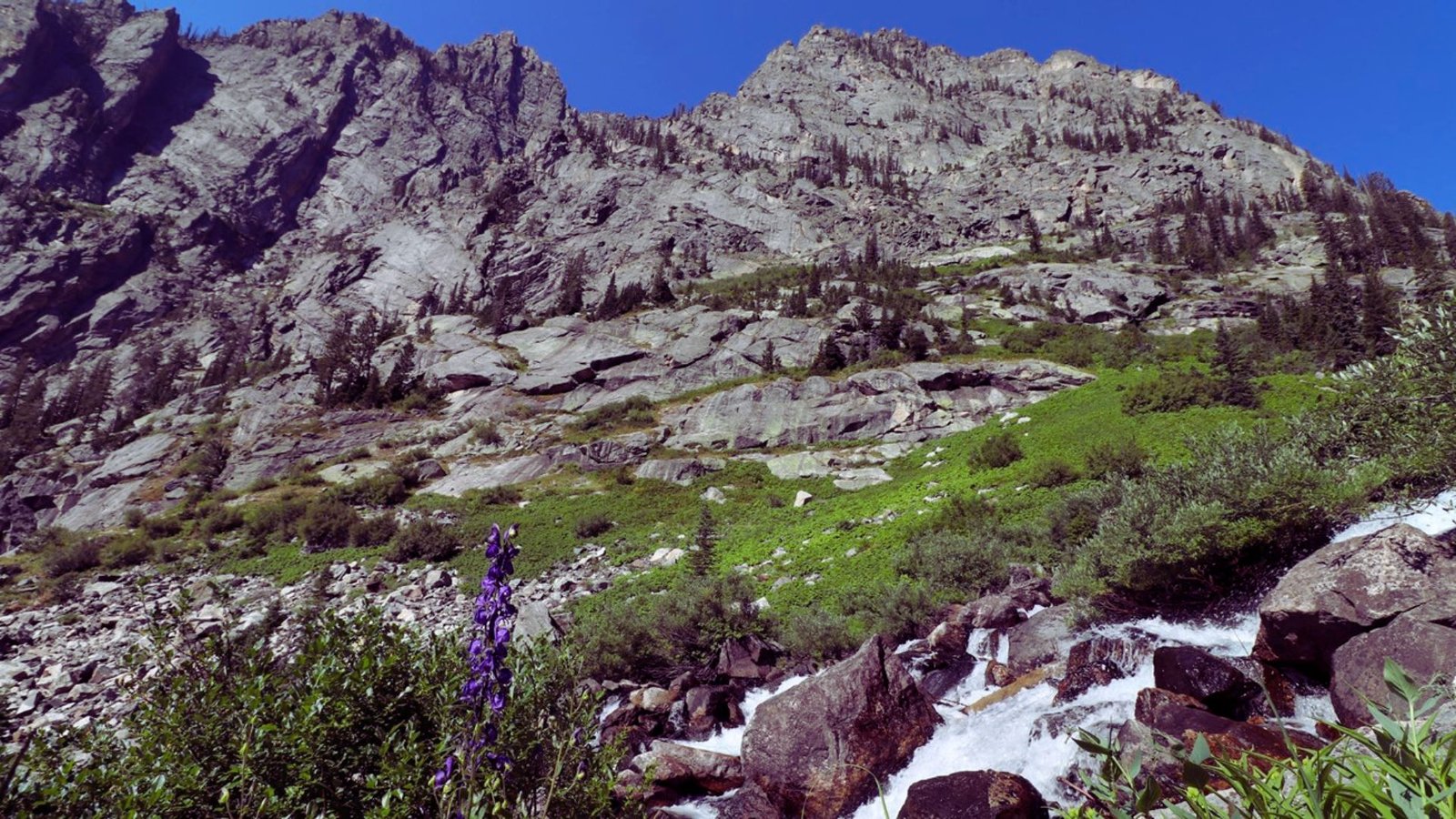  A majestic mountain with a cascading waterfall flowing down its rocky face.