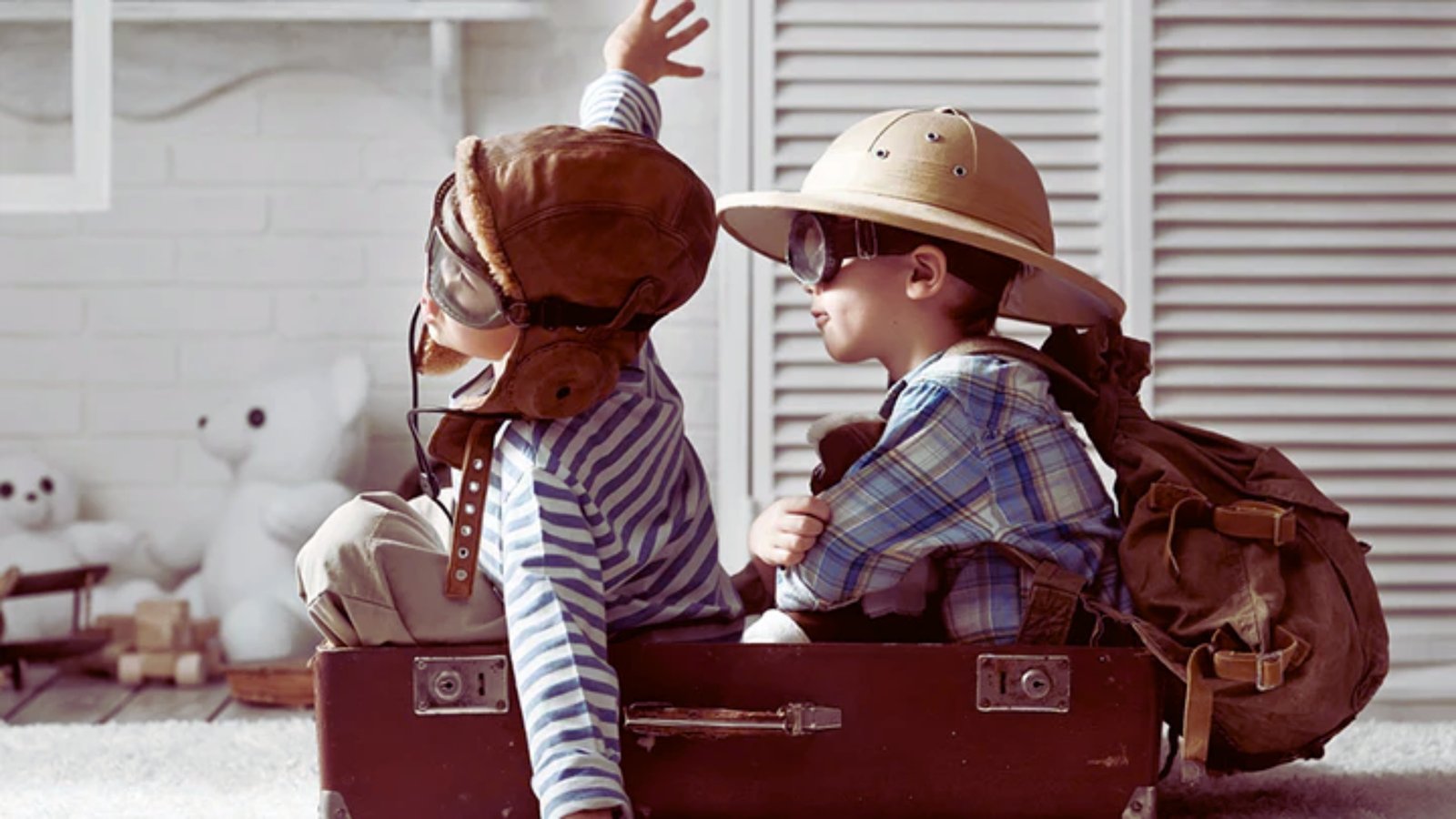 Two children play inside an open suitcase, smiling and enjoying their imaginative adventure.