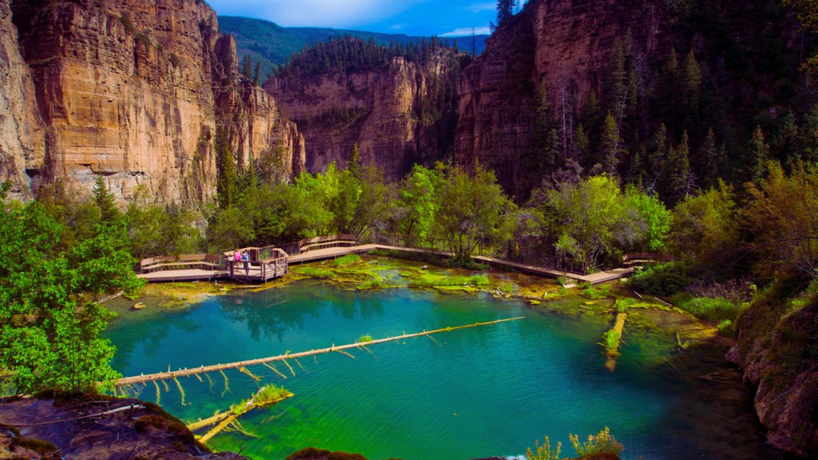 A scenic canyon bordered by lush trees and a tranquil body of water, showcasing nature's beauty and serenity.