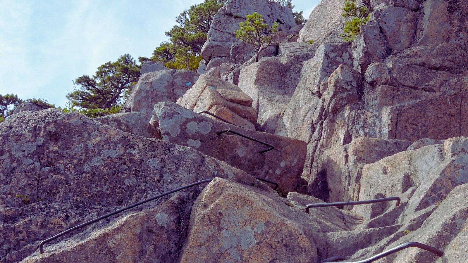 A climber ascends a rocky surface, secured by a rope, showcasing determination and skill in outdoor rock climbing.